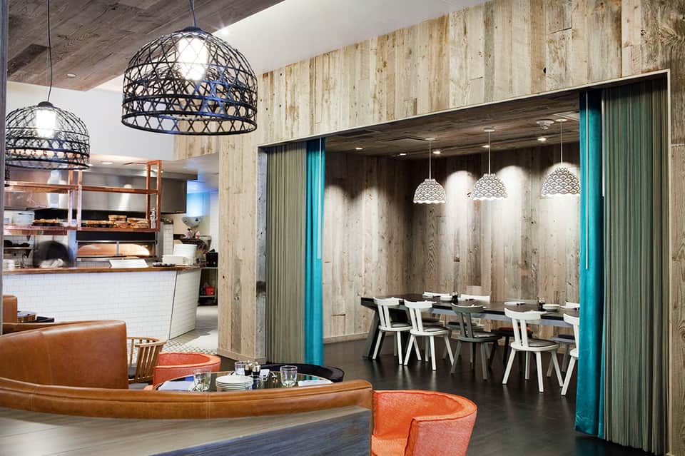 Modern hotel restaurant and bar with pendant lighting, wood walls, and turquoise accents