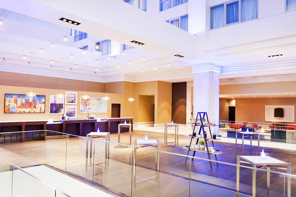 Modern hotel lobby and reception area with high ceilings, columns, artwork, and polished flooring