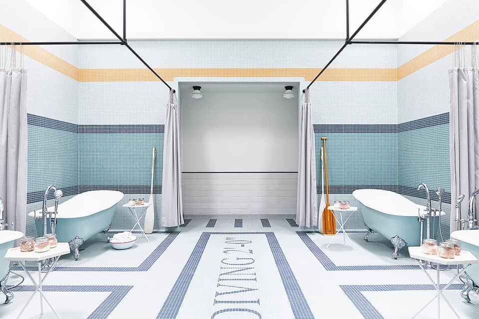 Elegant dual bathroom with turquoise bathtubs, blue tile walls, and marble flooring