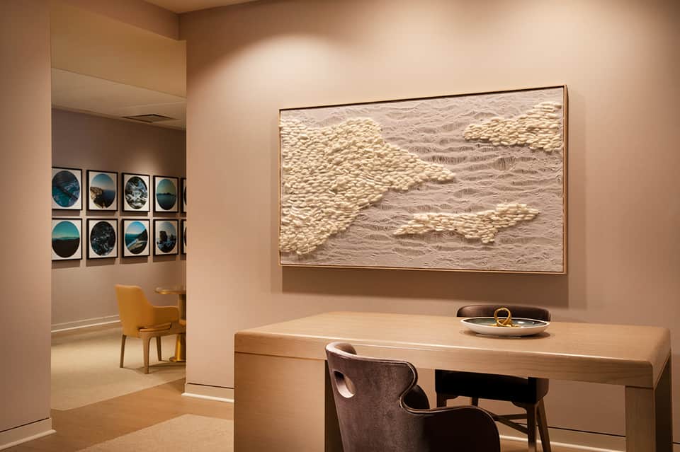 Contemporary office workspace with wooden desk, textured wall art, and window gallery of circular photos