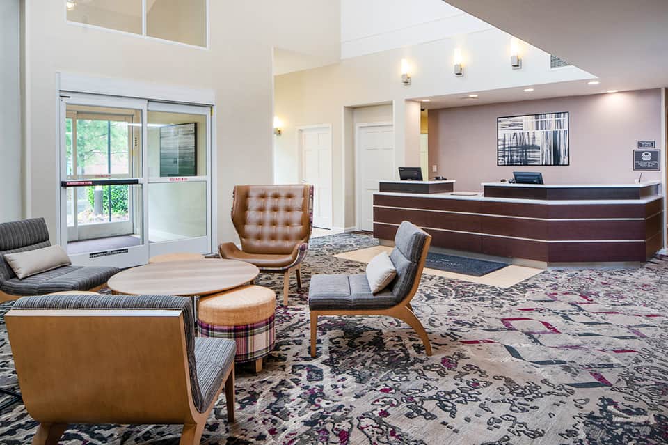 Modern hotel lobby with reception desk, leather seating, and floor-to-ceiling windows
