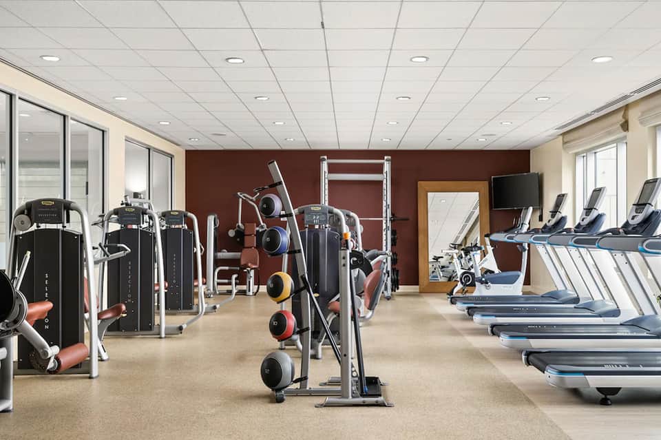 Well-equipped fitness center with cardio machines, weights, and televisions