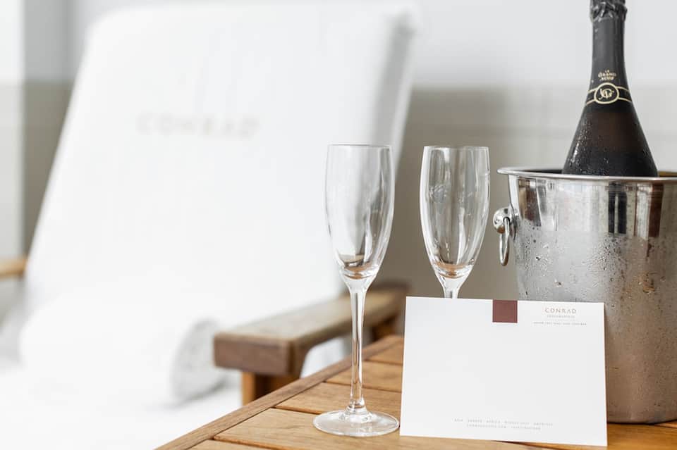 Champagne bottle and flutes on wooden table in luxury hotel suite