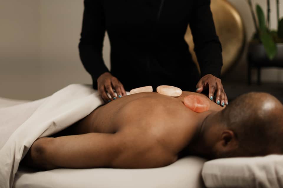 Spa treatment showing therapist performing hot stone massage on client's back