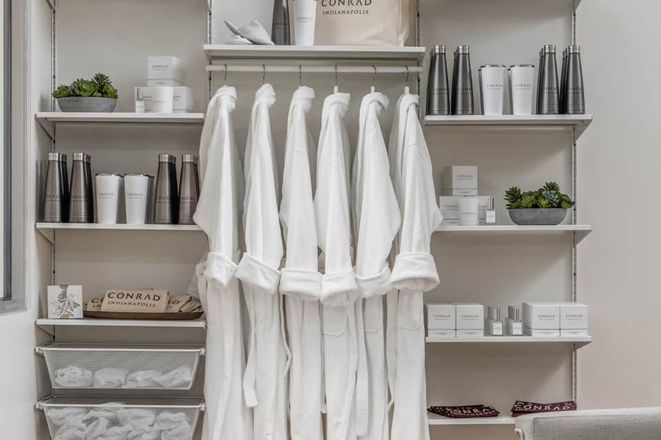 Spa amenities shelf display with white towels, Conrad branded products, and potted succulents