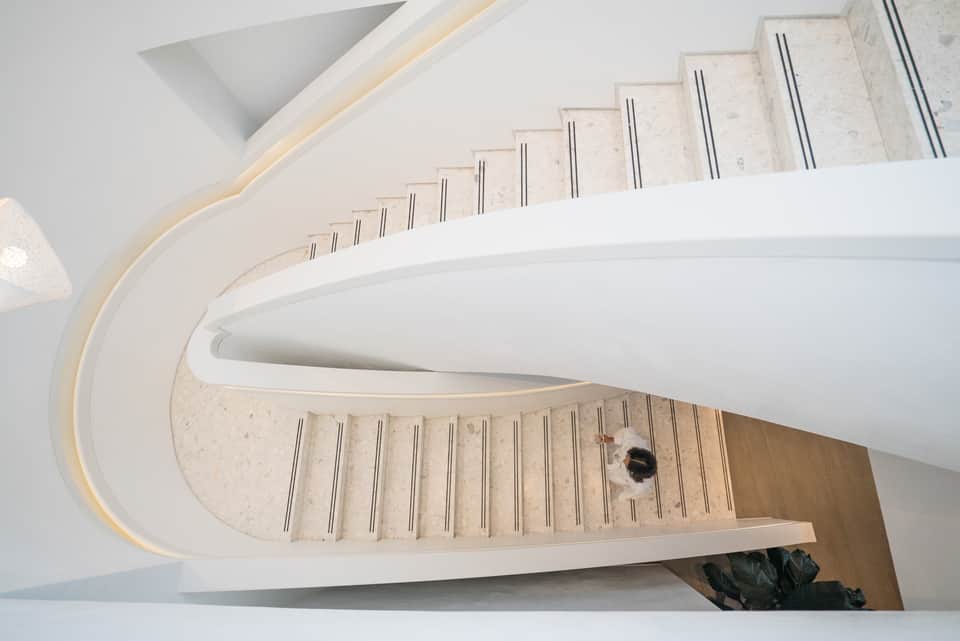 Modern spiral staircase with white walls, light wood steps, and contemporary architectural design