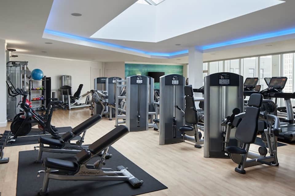 Modern fitness center with cardio equipment, strength machines, and blue accent lighting in ceiling