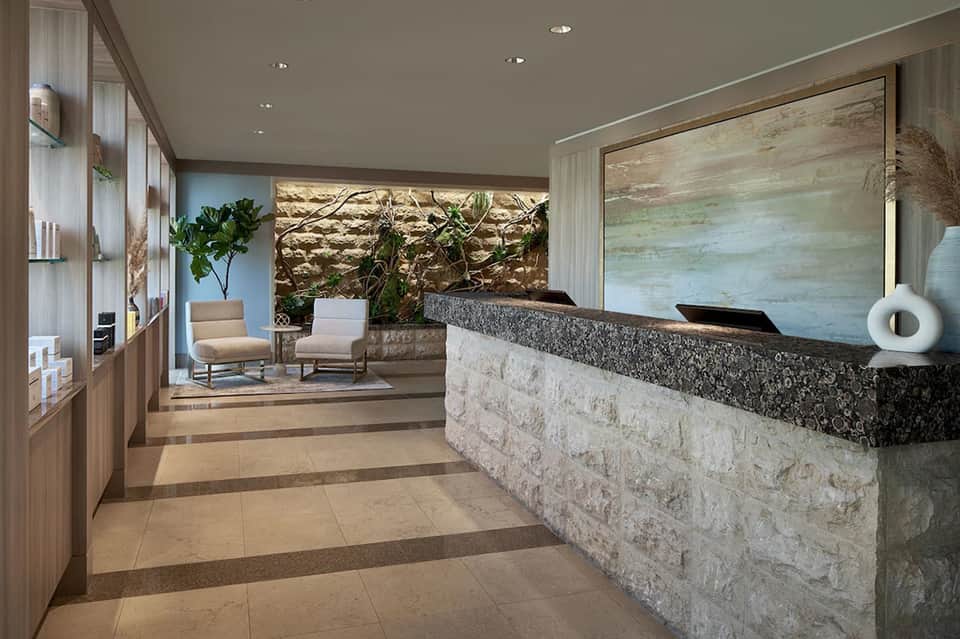 Modern hotel lobby with stone reception desk, wooden accents and contemporary furnishings