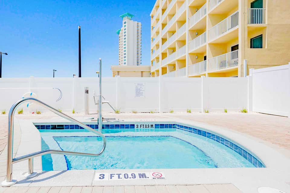 Rectangular pool with blue water and metal railings in front of yellow apartment building