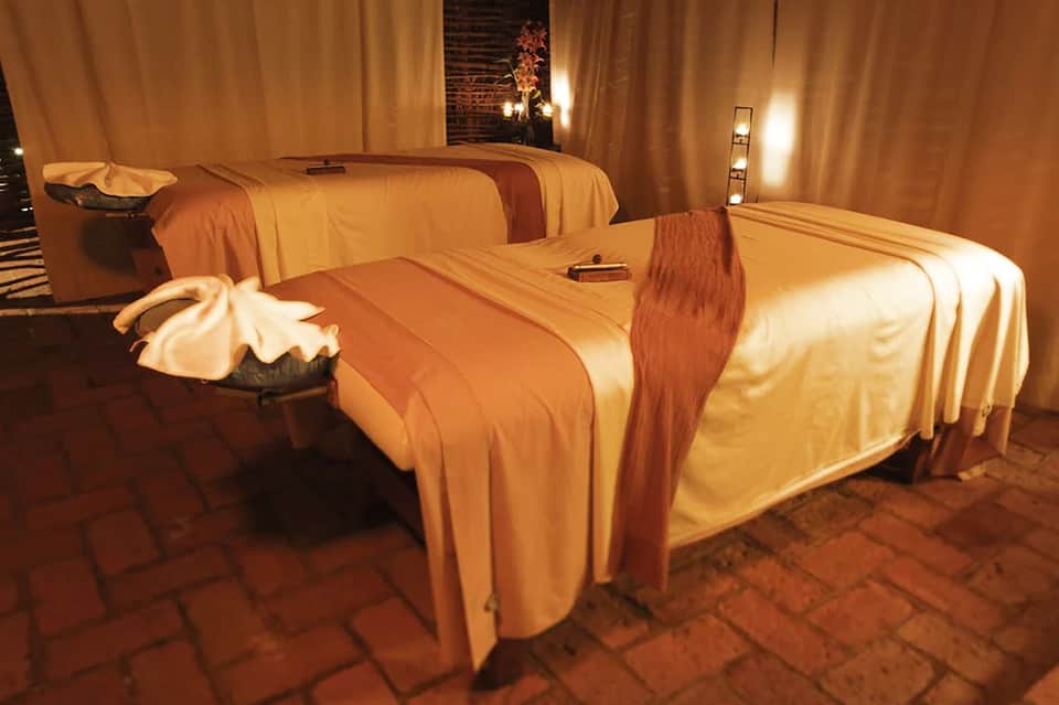 Luxurious spa treatment room with golden drapes and massage beds lit by warm lighting