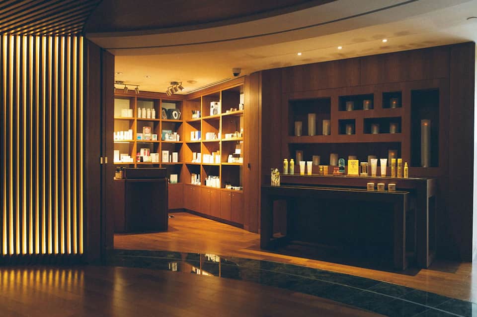 Luxury spa retail display with dark wood shelving, warm lighting, and beauty products
