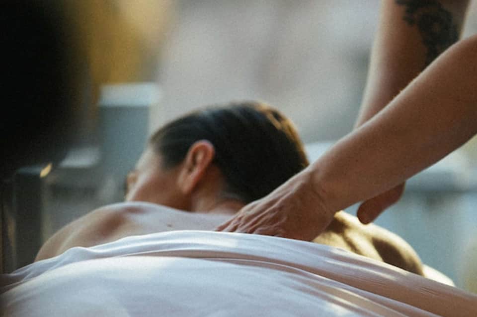 Spa therapist providing massage treatment to client on white table