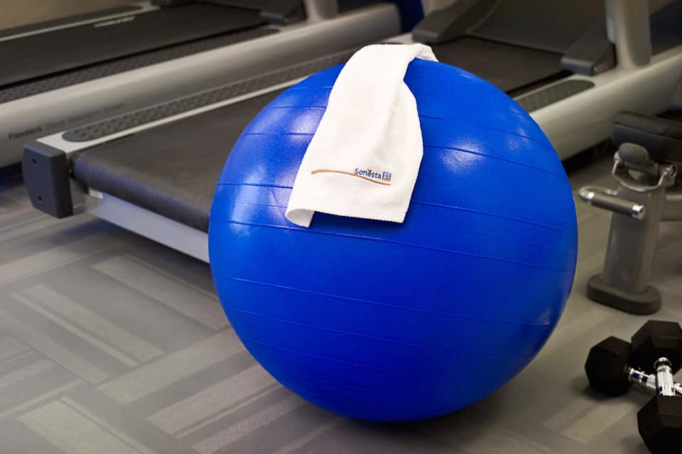 Blue exercise stability ball with white towel in bright, modern fitness facility