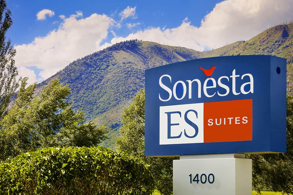 Sonesta ES Suites sign with mountains in background, blue and orange branding