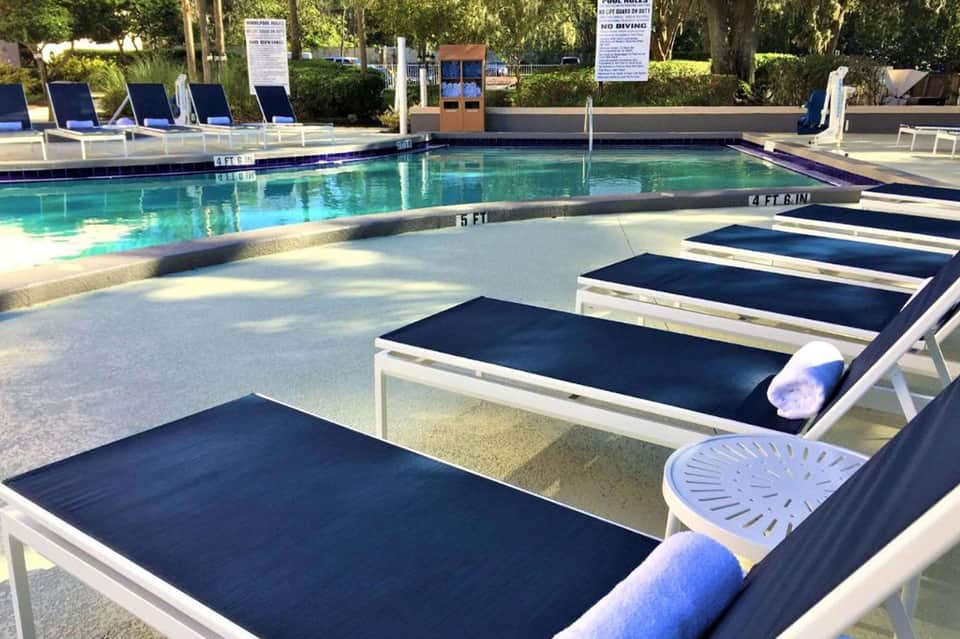Resort lap pool with loungers, shallow water feature, and landscaped poolside area