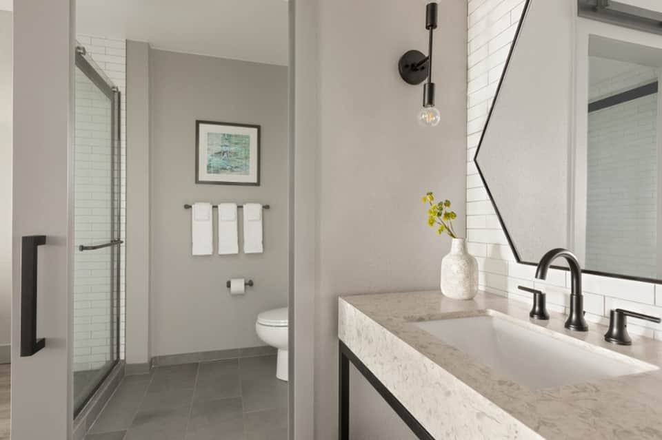 Modern bathroom with double vanity, marble countertop, and walk-in shower