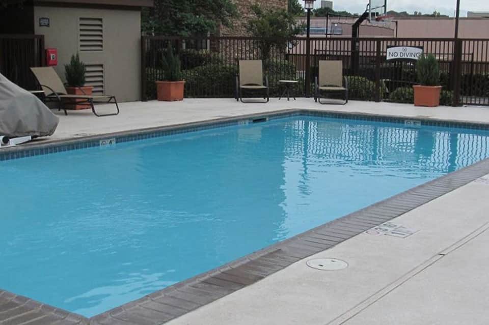 Rectangular swimming pool with lounge chairs, fencing, and no diving sign
