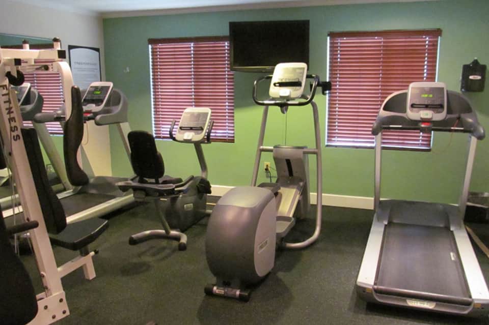 Fitness center with cardio equipment, treadmills, exercise bikes, and green accent walls