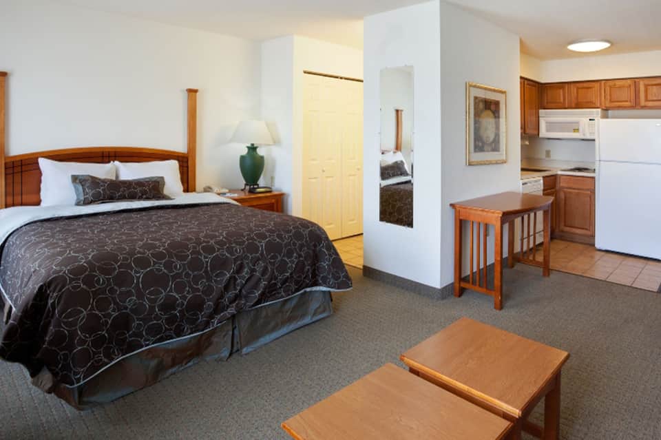 Suite room with queen bed, kitchenette, wood furnishings, and separate living area