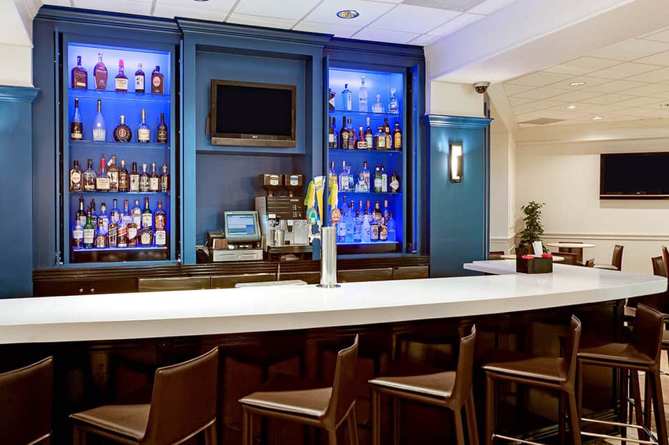 Modern bar with illuminated shelving displaying spirits and television screen