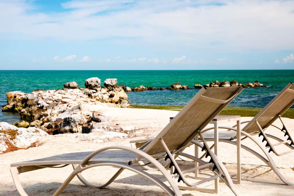 Beach lounge chairs overlooking turquoise ocean with white rocky formations
