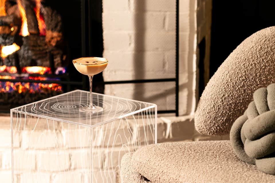 Elegant cocktail on geometric table by fireplace with comfortable upholstered seating