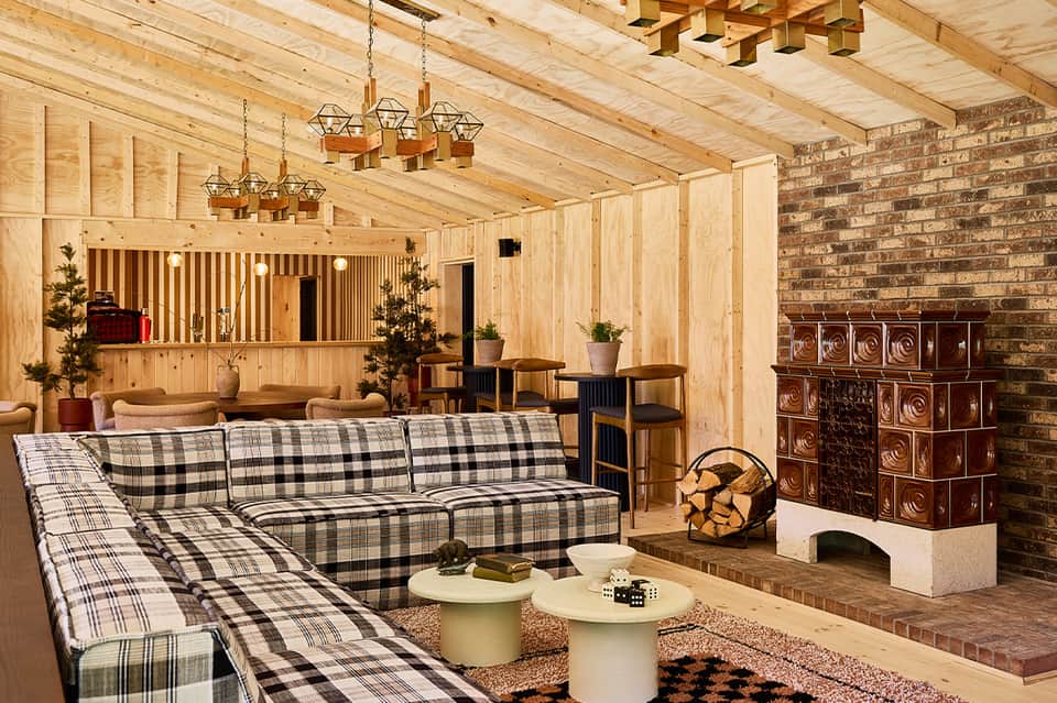 Rustic wooden lodge interior with plaid seating and decorative copper fireplace