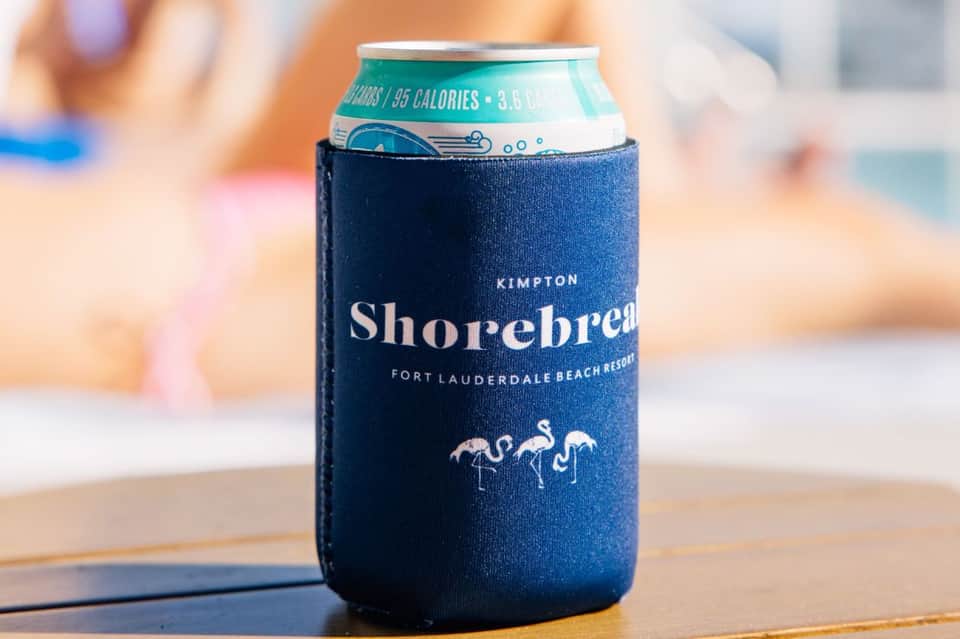 Shorbreak beer can with navy koozie on wooden surface with beach background