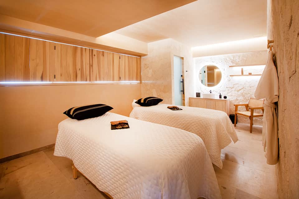 Minimalist luxury hotel room with two beds, natural wood accents, and marble bathroom