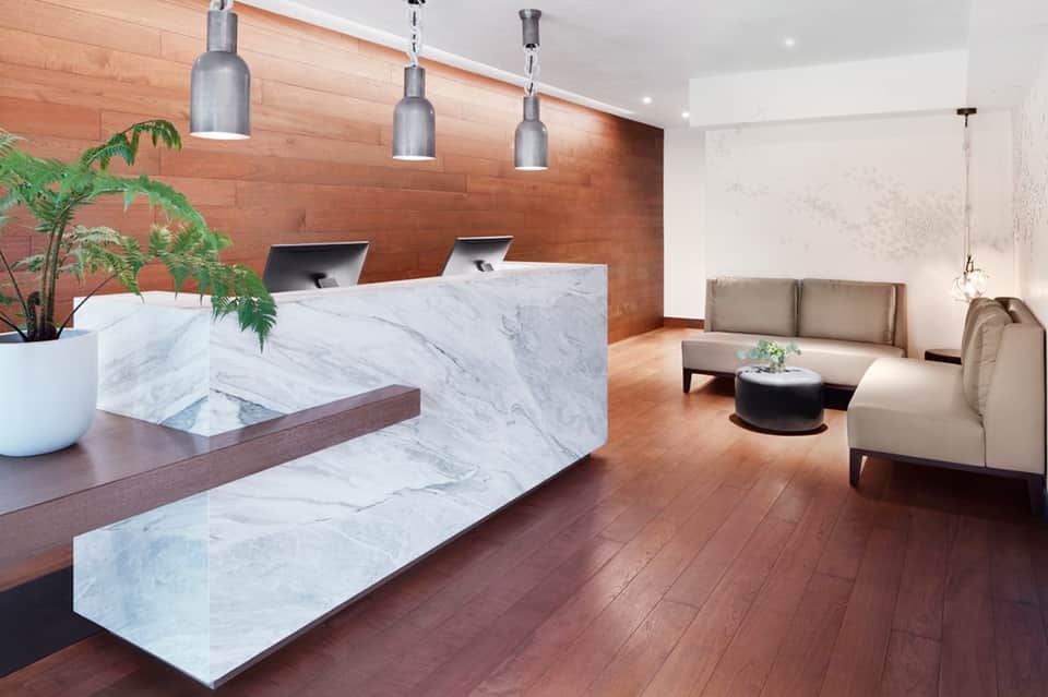 Modern hotel lobby with marble reception desk, wood accent wall, and contemporary furnishings