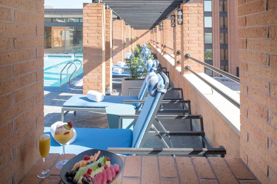 Poolside breakfast on brick terrace with fresh fruit plate, juice, and cocktail overlooking pool