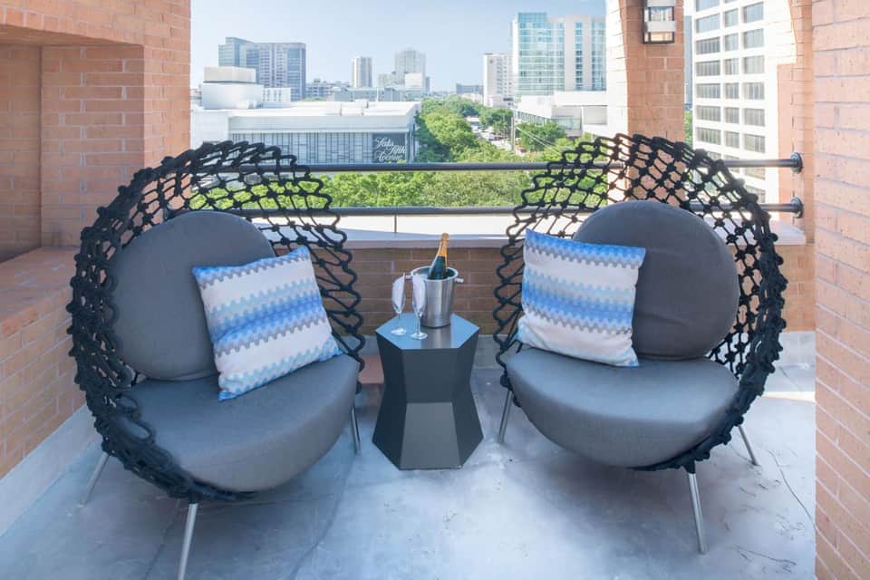 Hanging egg chairs on urban rooftop terrace with city skyline and champagne bottle