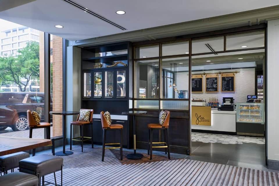 Hotel cafe interior with modern seating, floor-to-ceiling windows, and service counter