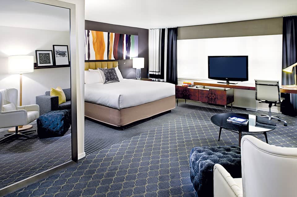 Modern hotel suite with king bed, workspace, and contemporary furnishings