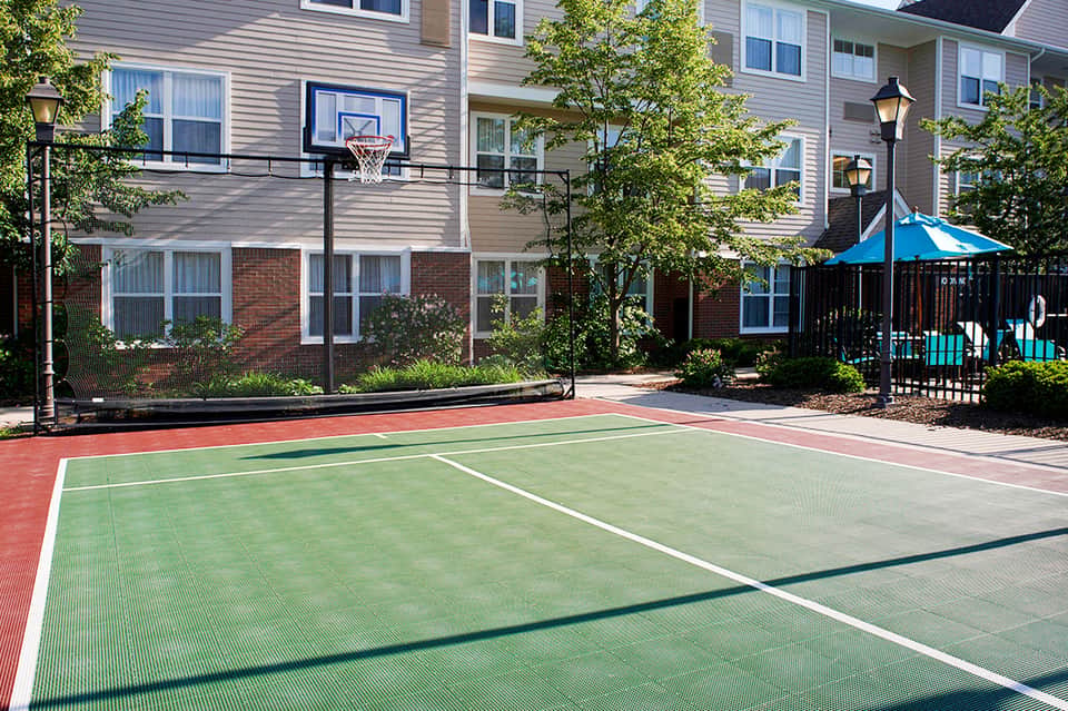 Sports complex with multi-colored basketball and tennis court near residential buildings