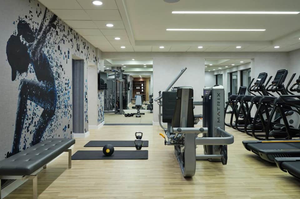 Fitness center with treadmills, weight equipment, artistic wall mural, and modern design
