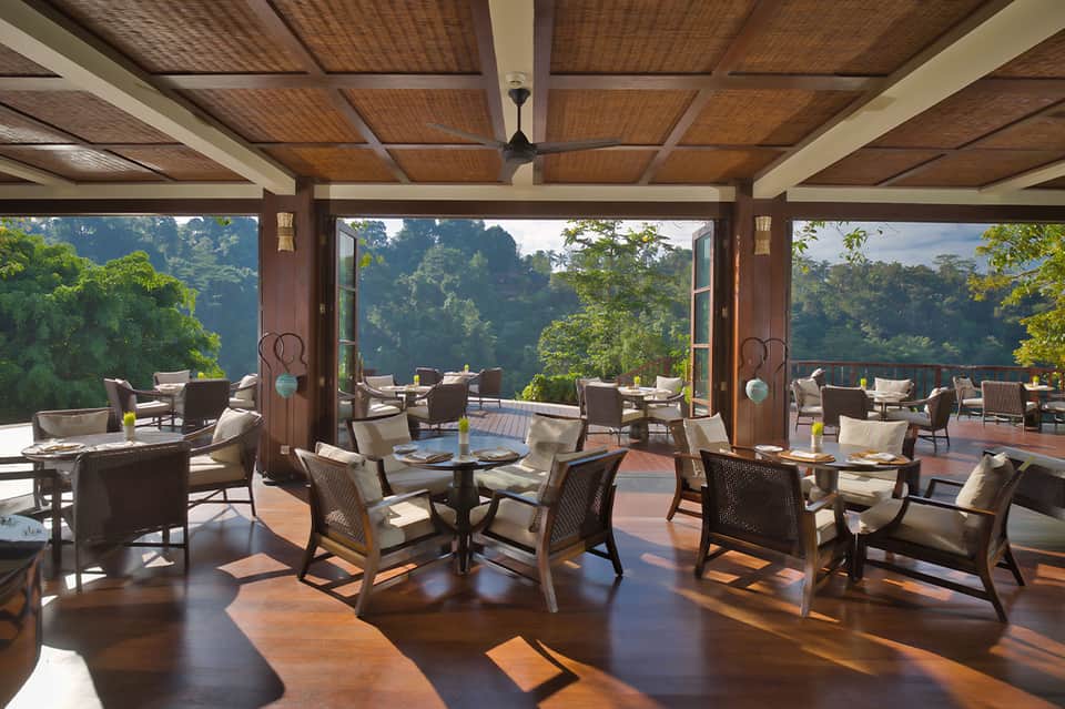 Modern lounge pavilion with wood ceiling, rattan chairs, and panoramic forest mountain views