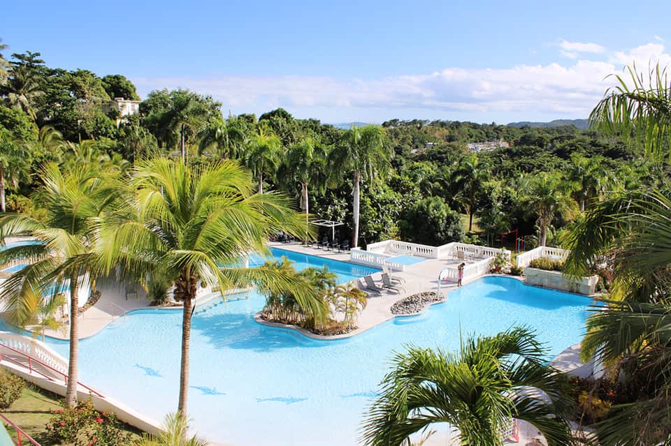 Multi-level resort pool complex with palm trees and scenic landscape view