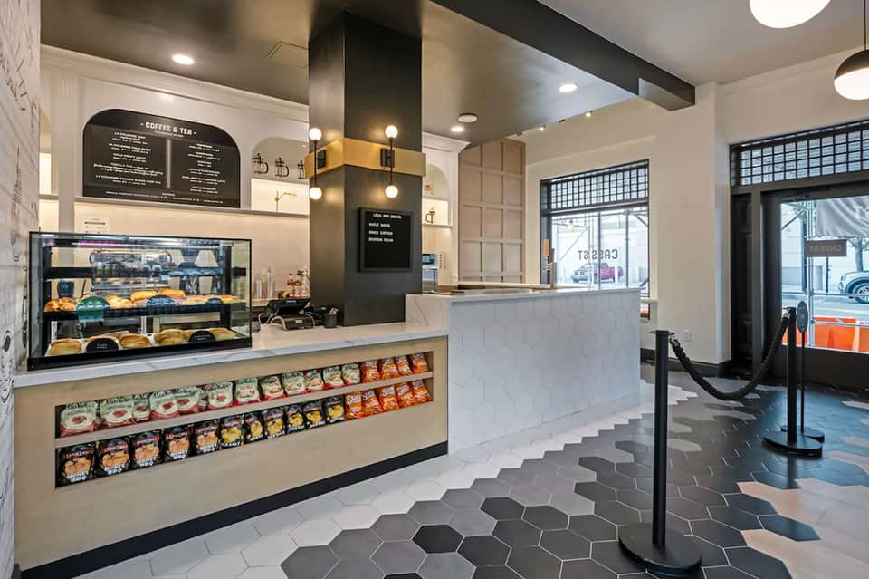 Modern hotel cafe interior with display case, marble counter, and black tile flooring