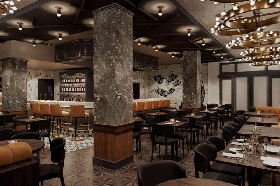Upscale restaurant interior with dark ceiling, marble columns, brown leather chairs, and crystal chandelier