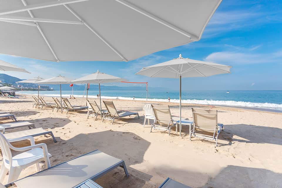 Sandy beach with white umbrellas, lounge chairs, and ocean view