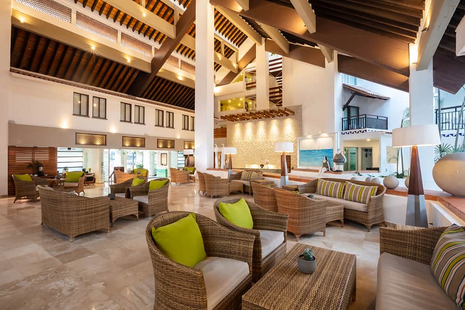 Spacious hotel lobby with soaring ceiling, woven furniture, lime green accents, and natural light