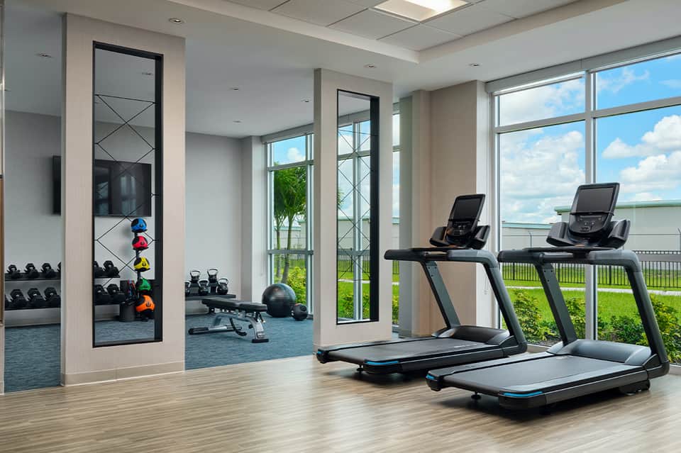 Fitness center with treadmills, weights, and floor-to-ceiling windows overlooking water