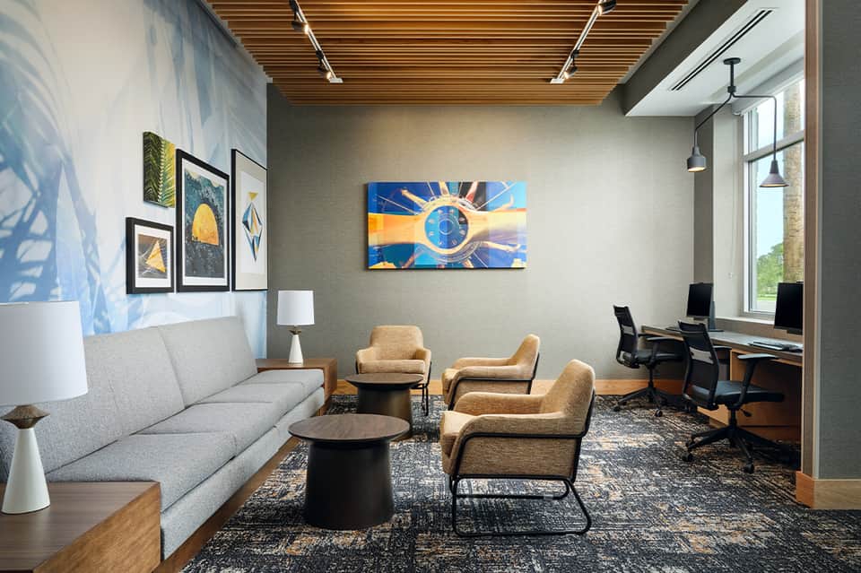 Contemporary business lounge with modern artwork, wooden ceiling, and work stations