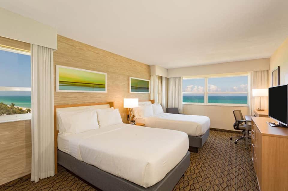 Beachfront hotel room with two queen beds, ocean views, and natural wood accents