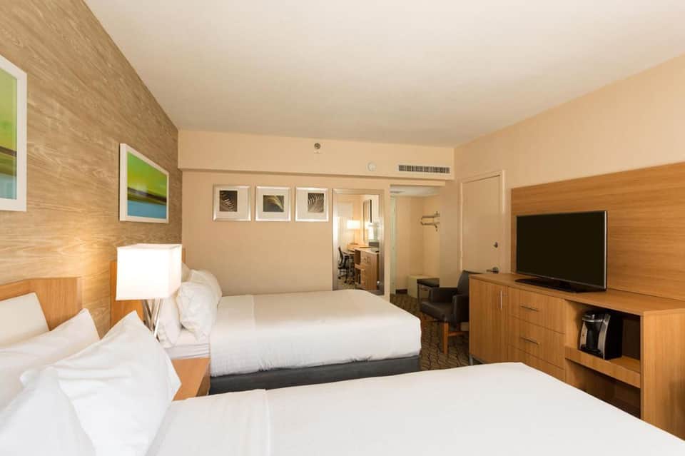Hotel guest room with two beds, wood accents, flat-screen TV, and contemporary furnishings