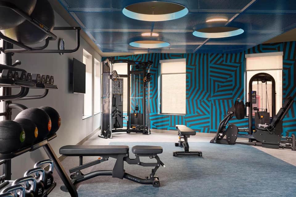 Modern hotel fitness center with blue geometric wall patterns, exercise equipment, and contemporary design