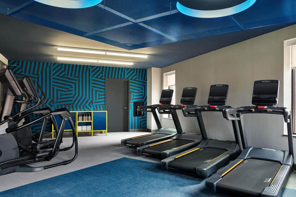 Modern fitness center with treadmills, blue geometric ceiling design, and contemporary decor