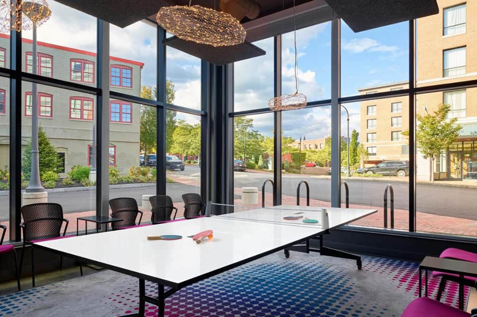 Contemporary meeting room with large windows, white table, black chairs, and city views