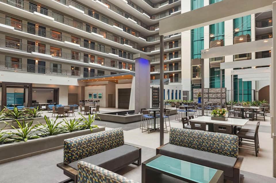 Modern hotel atrium courtyard with multi-level balconies, lounge seating, and contemporary architectural design